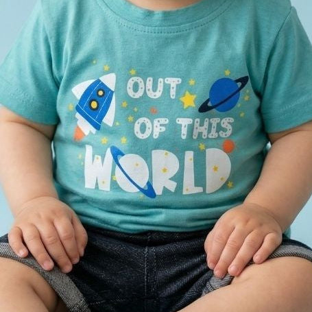 Child wearing a blue t-shirt with 'Out of this World' text and space-themed graphics on a light blue background.